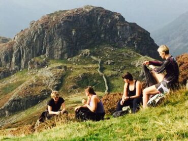 4 people sta relaxing backdrop mountains lake district