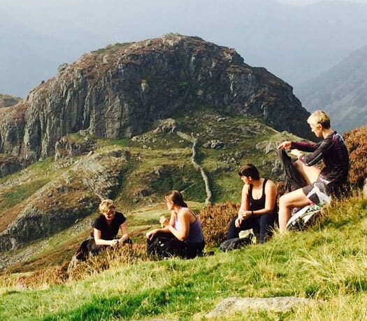4 people sta relaxing backdrop mountains lake district