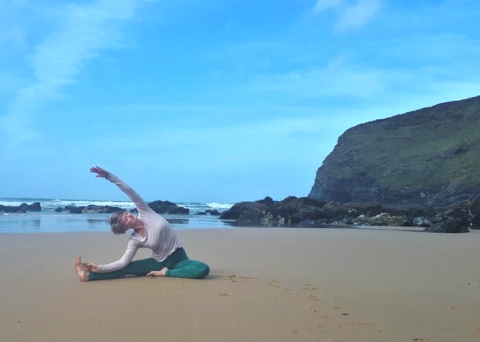 seated side bend on beach cliffs and sea cornwall