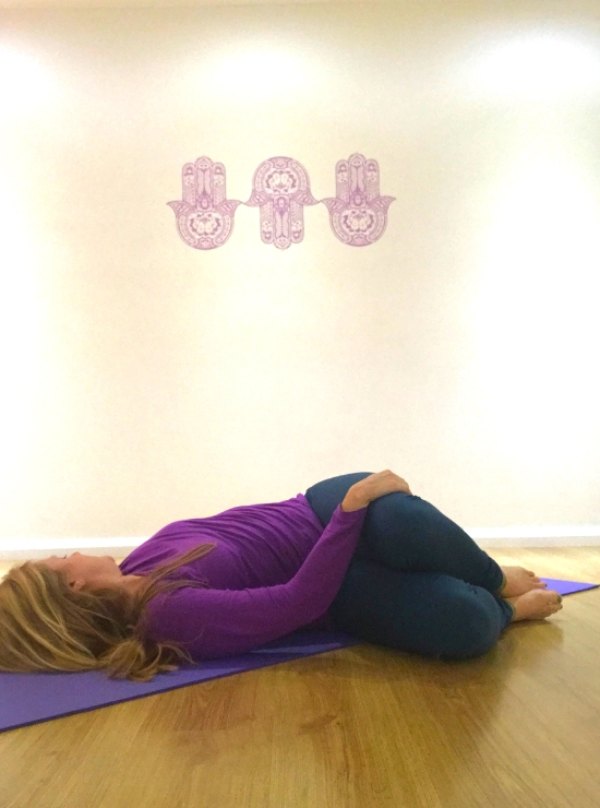 person twisting legs to the right head to left supine twistyin yoga ease back pain