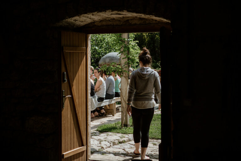 person walking out door to people seated outside - hiking yoga holiday montenegro
