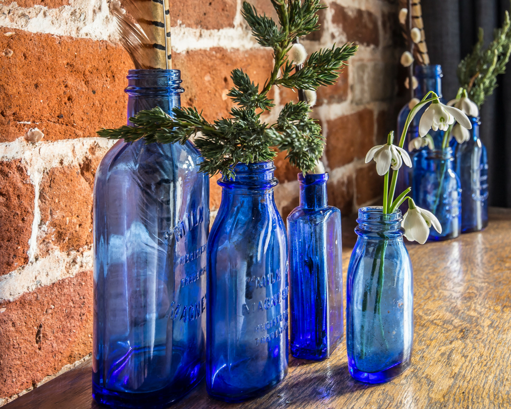 Blue transparent bottles with feathers and flowers in