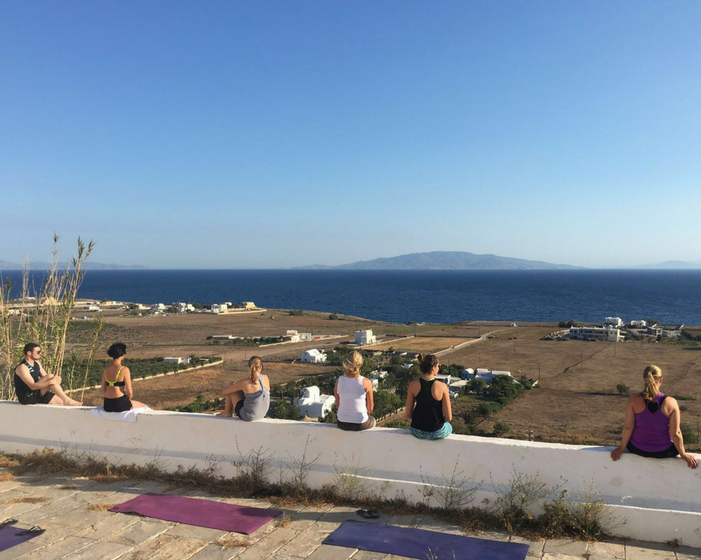 Yogis meditating on wall overlooking sea
