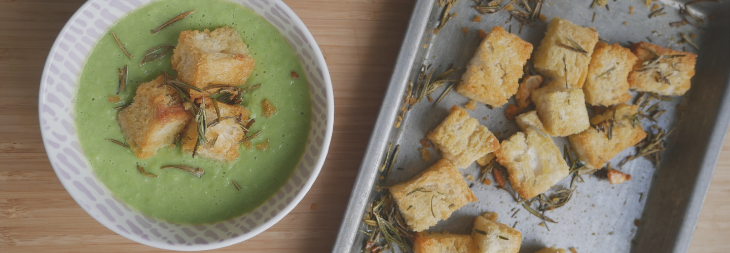 bowl of green colour soup tray of croutons