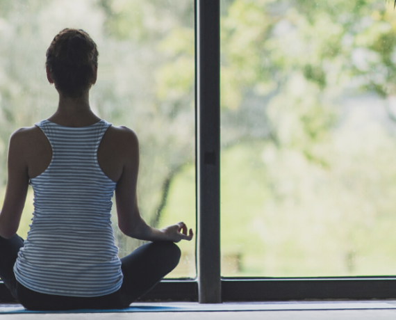 woman sat meditation pose looking out window