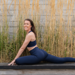 woman doing pigeon yoga pose on floor reeds in background