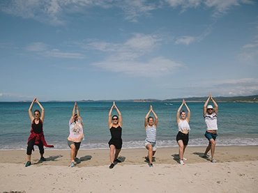 people doing yoga pose on the beach in sardinia