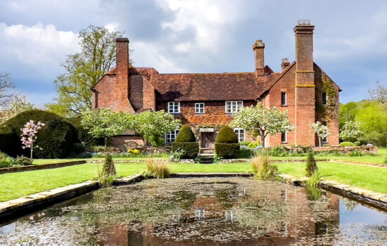 old manor house with lawn and pond in front