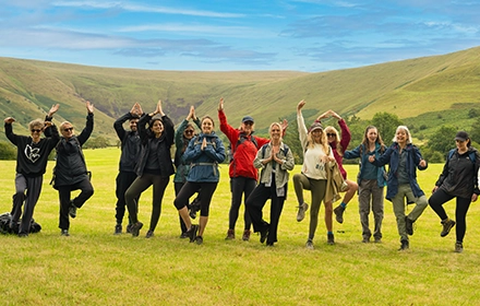 people doing yoga pose outside with brecon beacons behind them