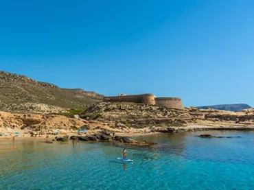 someone paddle boarding in clear water in almeria spain