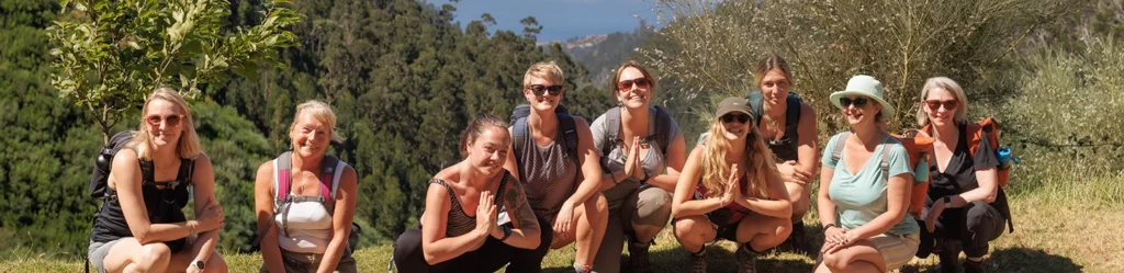 group of women doing seated yoga post amongst madeira countryside